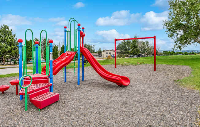 a playground with a red slide and monkey bars in a park