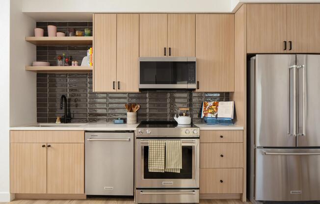 Light wood cabinetry, sleek stainless appliances, and a glossy tile backsplash create a clean, contemporary kitchen with character.