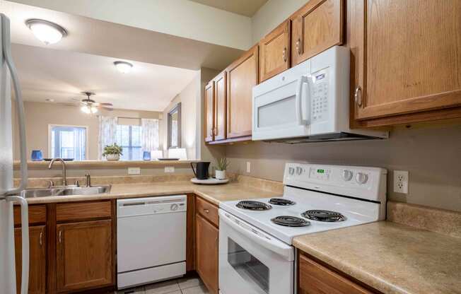 kitchen with white appliances and wooden cabinets at the whispering winds apartments in pearland, tx