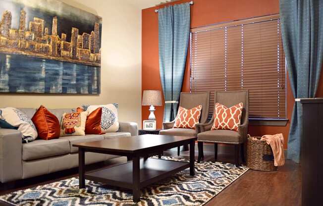 A living room with a grey couch, a coffee table, and a cityscape painting on the wall.