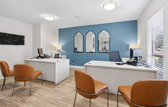 A room with a white desk and orange chairs.