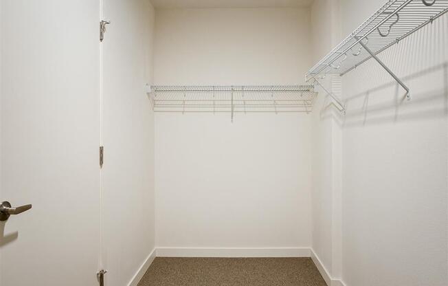 a room with white walls and a closet with wire shelving