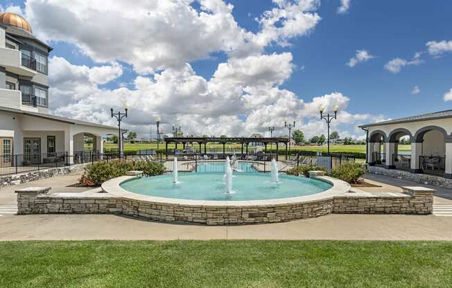 a fountain in the middle of a pool in front of a building