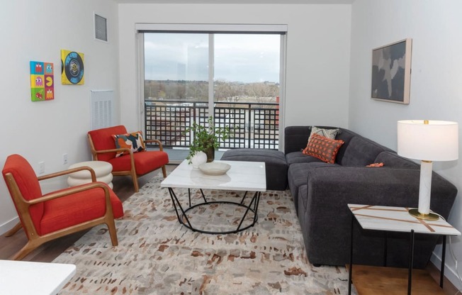 a living room with a large window and a couch and chairs