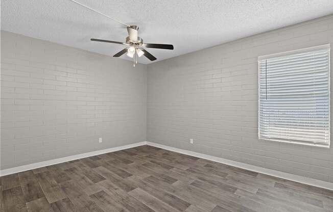 A room with a ceiling fan and a window with blinds.