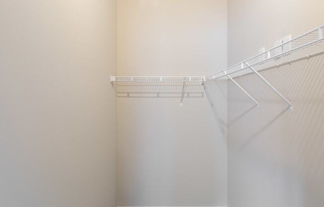 an empty walk in closet with white shelves and a white wall with a wire rack