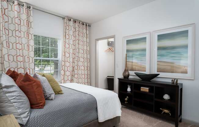 Two-Bedroom Apartments in Canal Winchester, OH - The Coleman - Furnished Bedroom with a Large Bed, Carpet Flooring, a Dresser, a Window, a Closet, and Stylish Decor