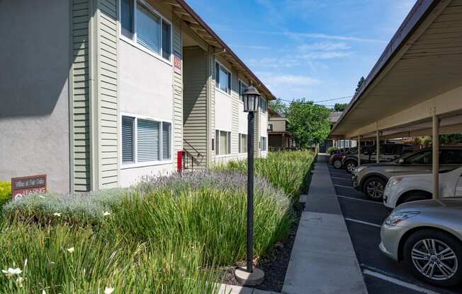 View of exterior of building with blooming shrubbery and covered parking