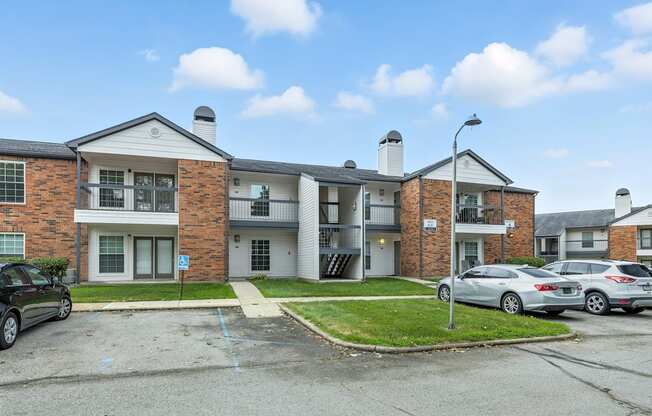 A parking lot in front of a brick apartment building.