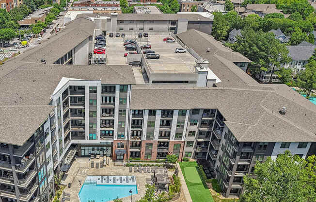 An aerial view of 915 Glenwood apartments with a swimming pool, green area with walking path,  and a parking lot.