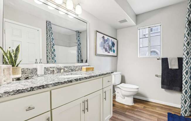 A bathroom with a marble countertop and white cabinets.
