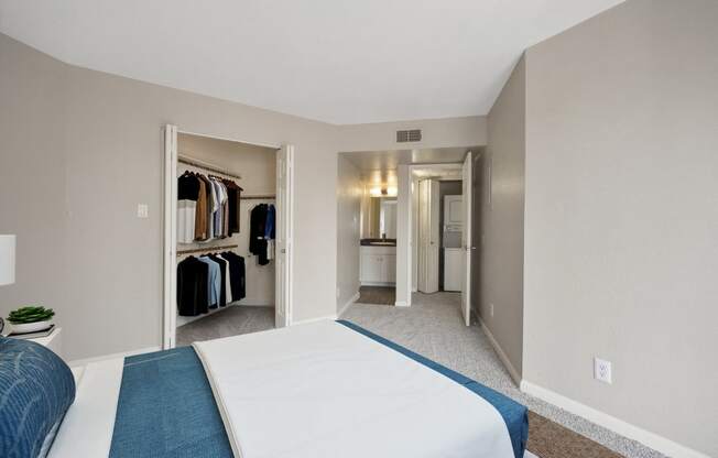 a bedroom with a large bed and a closet with clothes racks