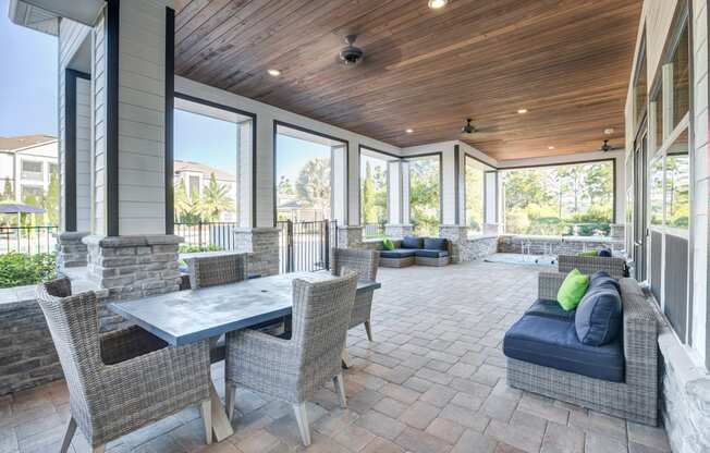 a covered patio with wicker furniture and large windows