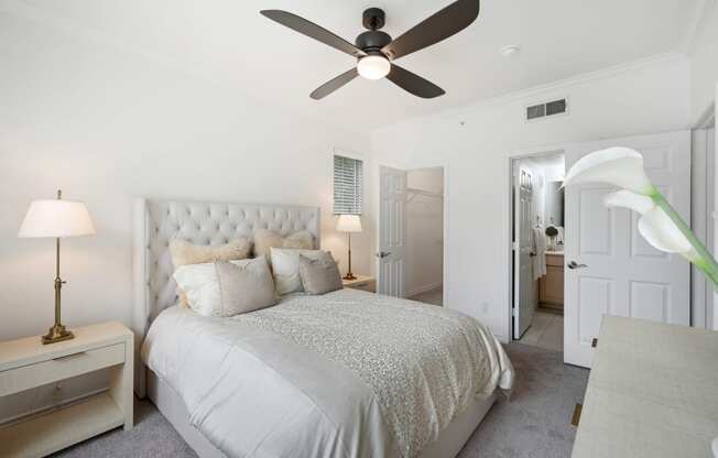 a white bedroom with a bed and a ceiling fan