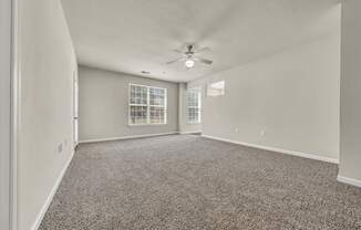 an empty living room with carpet and a ceiling fan