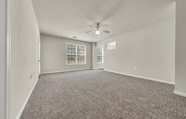 an empty living room with carpet and a ceiling fan