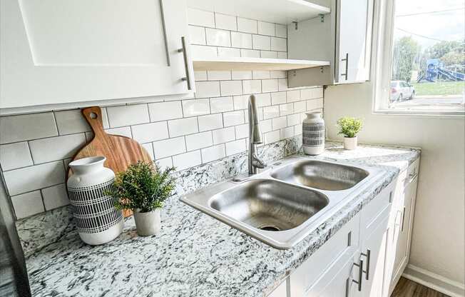a kitchen with white cabinets and a counter top with a sink