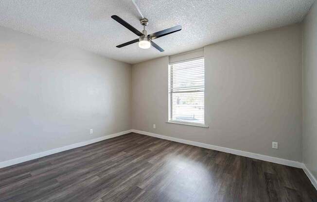 A room with a ceiling fan and a window with blinds.