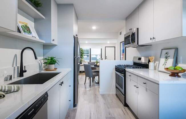 A modern kitchen with white cabinets and a wooden floor.