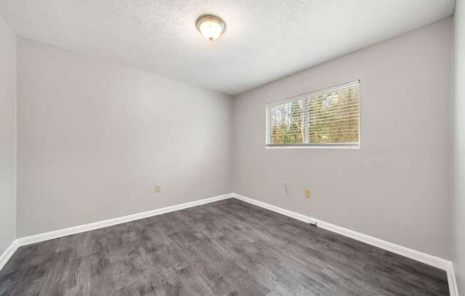an empty room with wood flooring and a window