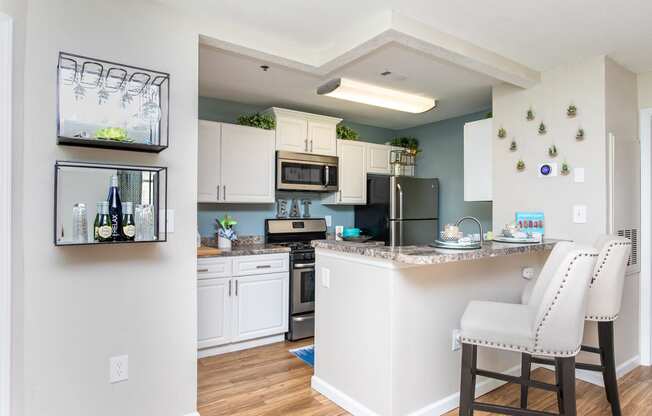 an open kitchen and dining area with white cabinets and stainless steel appliances