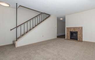 an empty living room with a staircase and a fireplace at Lincoln Village Apartments, Spokane