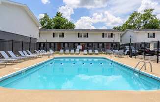 A large swimming pool in front of a building with lounge chairs around it at Spring Creek Townhomes Apartments, Springfield, IL