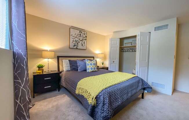 A bedroom with a bed, nightstands, and a painting on the wall.