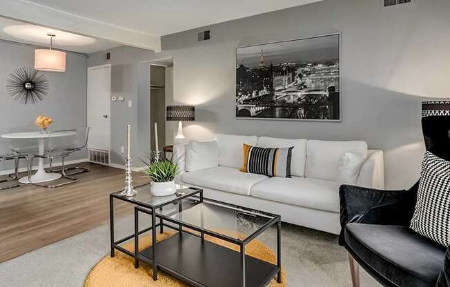 A living room with a white couch, a coffee table, and a black and white photo on the wall.