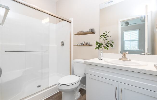 a bathroom with a white sink and toilet next to a shower with a glass door