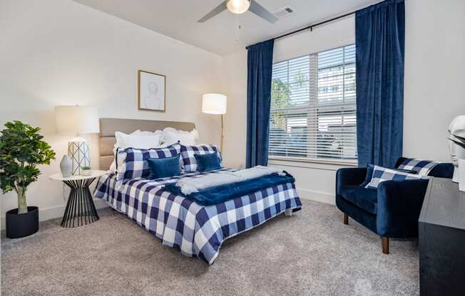 a bedroom with a bed and a chair and a ceiling fan at The Quincy Apartments, Acworth, Georgia