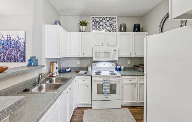 A white kitchen with a sink and a refrigerator.
