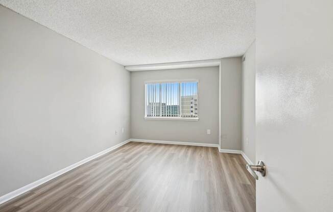 A room with a window and wooden flooring.