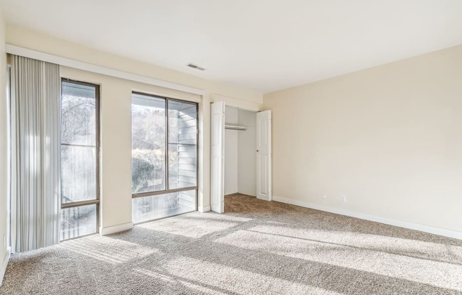 A sunny day with a room having a carpet and a sliding glass door.