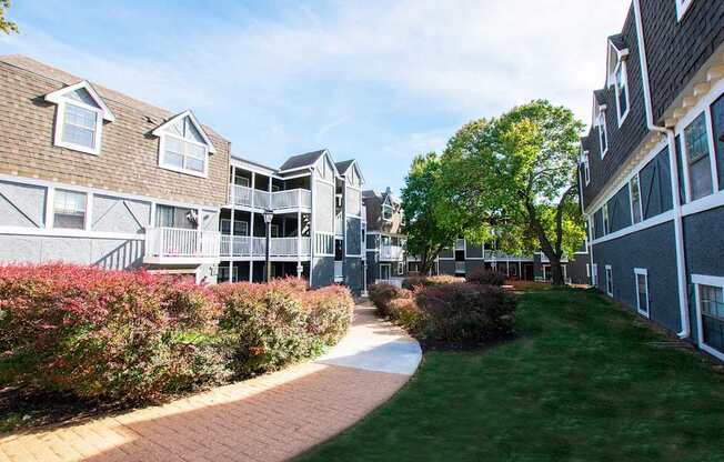 A pathway leads through a grassy area between two buildings.