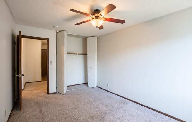the living room of an empty apartment with a ceiling fan.   Eagan, MN Glen Pond Apartments