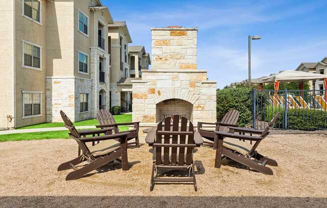 A fireplace is in the middle of three chairs on a patio.