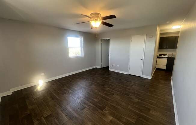 an empty living room with wood floors and a ceiling fan