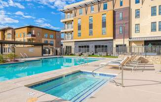 A swimming pool in front of a multi-story apartment building.