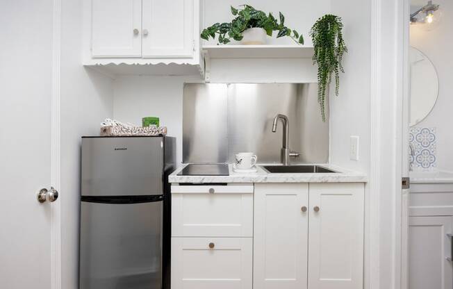 a small kitchen with white cabinets and a stainless steel refrigerator