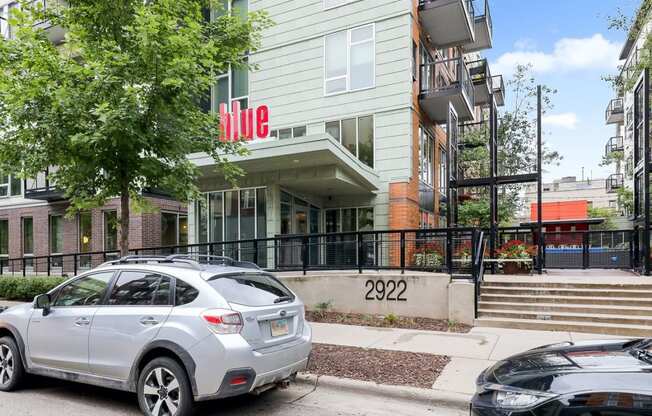 an apartment building with a silver car parked in front of it