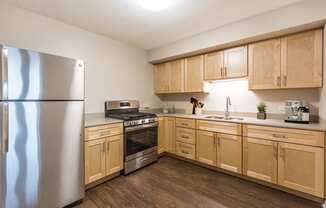 Kitchen with stainless steel appliances, light wood cabinetry, and plan flooring