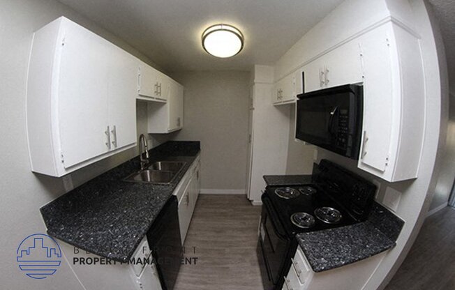 a small kitchen with white cabinets and black counter tops