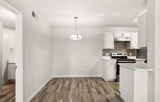 an empty kitchen with white appliances and a wood floor