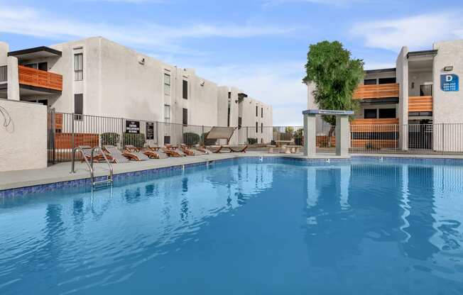 a large swimming pool with lounge chairs and a building in the background