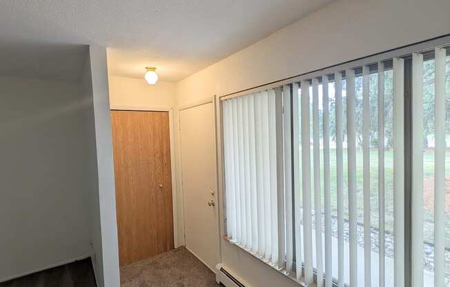 A room with a brown door and a window with blinds.