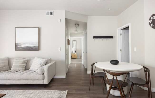 a small table and chairs in a living room with a couch and a hallway in the background