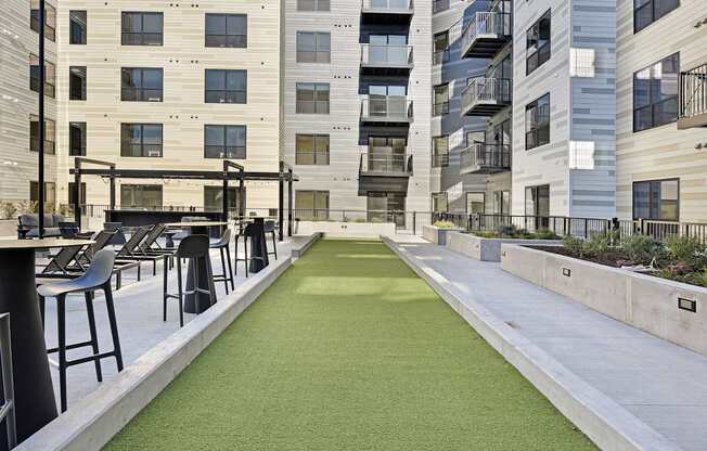 A miniature golf course is located in the courtyard of a modern apartment complex.