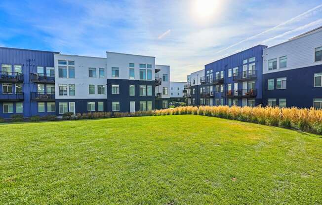 A sunny day at a grassy field with apartment buildings in the background.