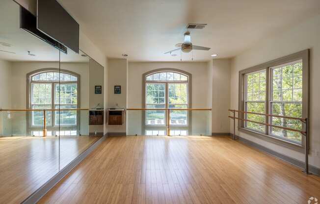 an empty living room with a hard wood floor and large windows
